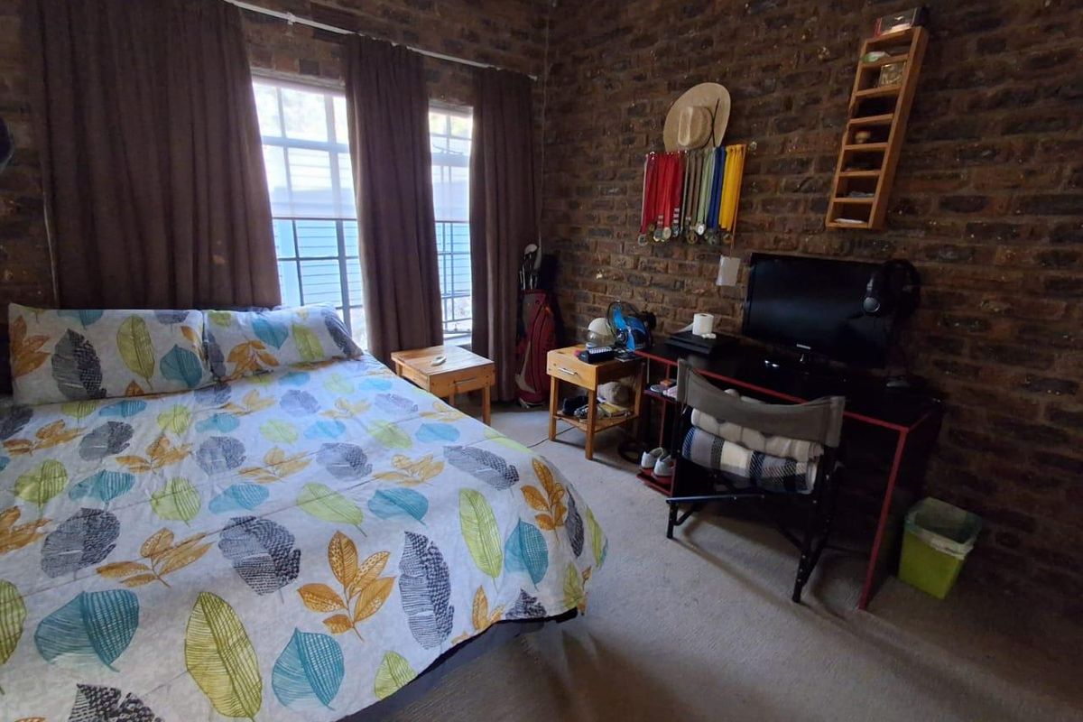 A bedroom featuring a prominent exposed brick wall and large windows, providing a rustic aesthetic with natural light.