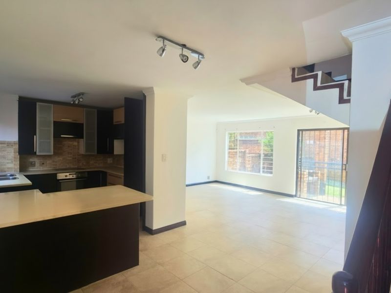 Spacious open-plan kitchen and living area featuring tiled floors, modern cabinetry, built-in appliances, and a staircase leading to the upper level.