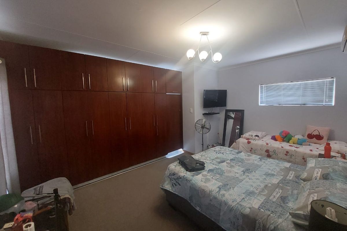 Spacious bedroom featuring extensive wall-to-wall built-in wooden cabinetry, neutral carpeting, and a horizontal window with fitted blinds.