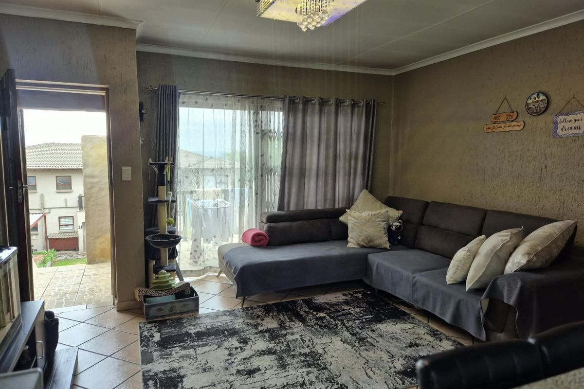 A living room featuring tiled flooring, a crystal chandelier, and a sliding glass door providing access to an outdoor balcony area.