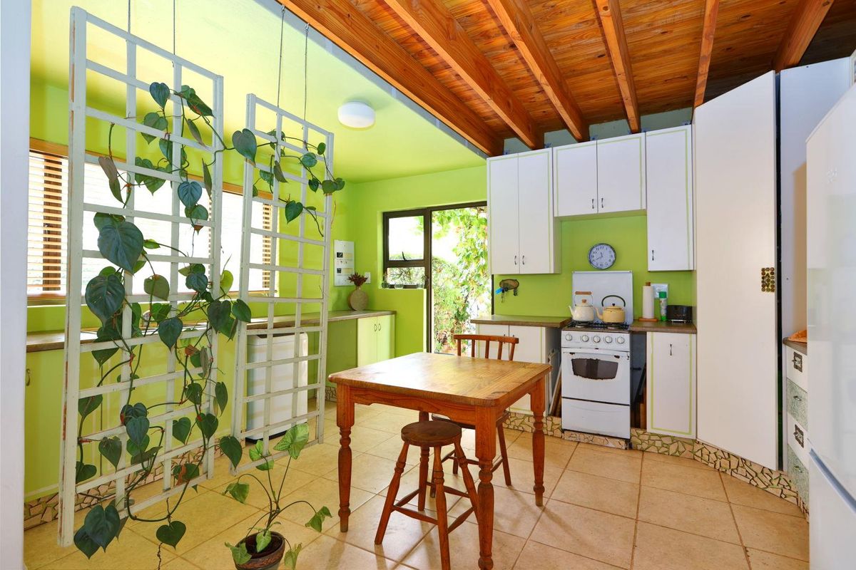 A kitchen featuring exposed timber ceiling beams, white cabinetry, and tiled flooring, with direct access to an outdoor area.