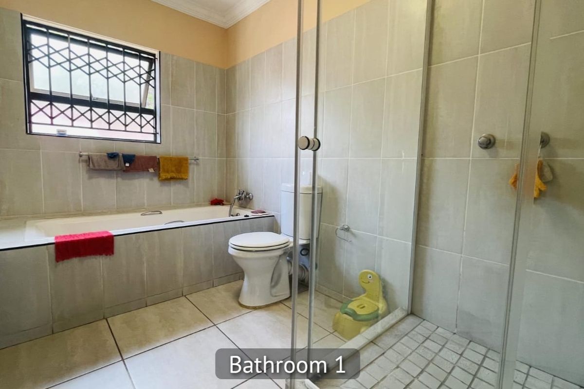 A functional bathroom featuring a built-in bathtub, a separate glass-enclosed shower, and neutral wall and floor tiling.