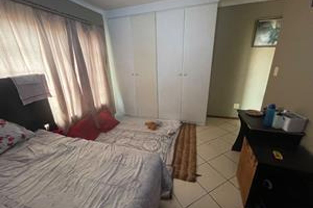 A bedroom featuring built-in cupboards and tiled flooring, offering a functional space with neutral wall tones.