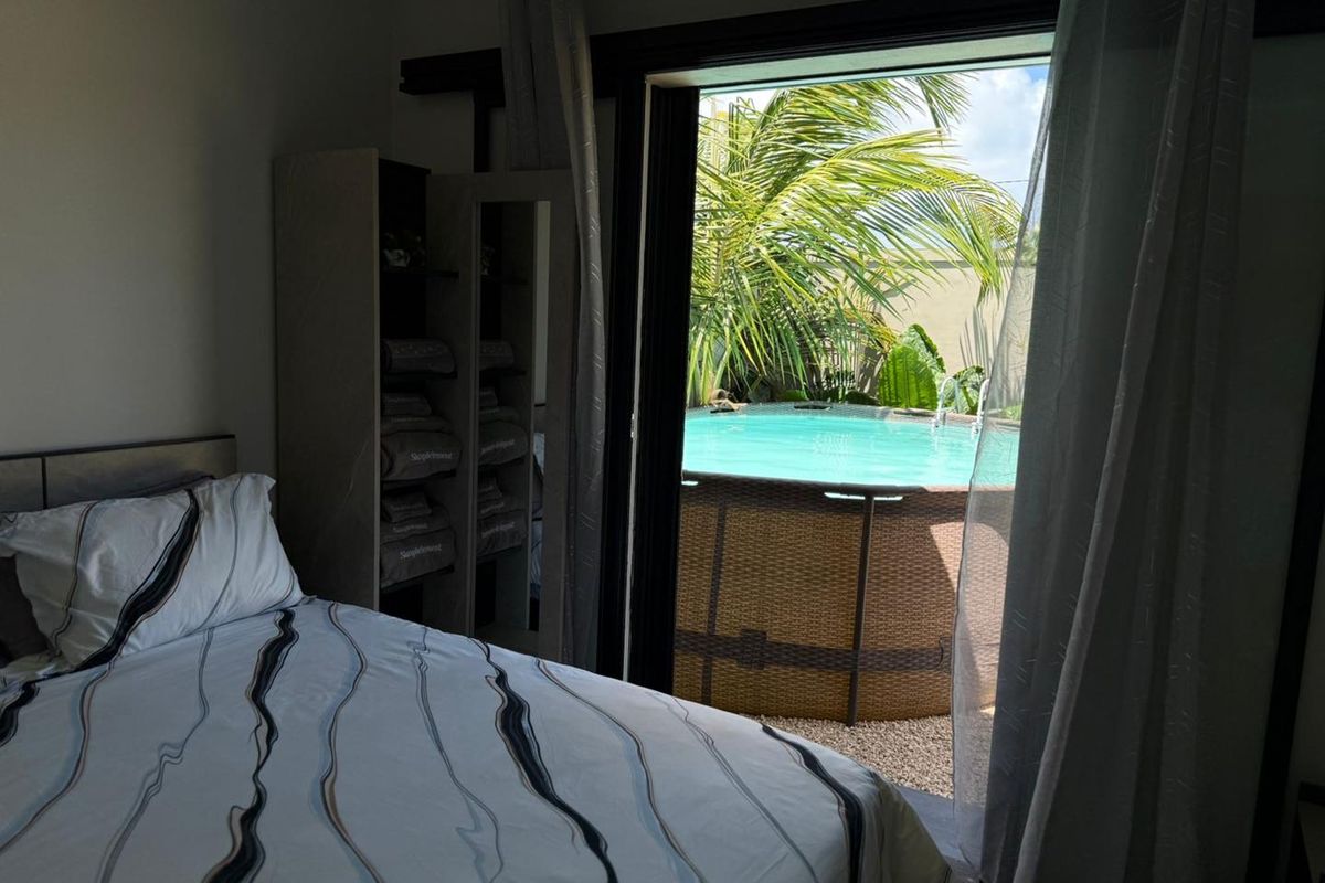 A bedroom featuring sliding glass doors that open directly to a private outdoor area with a swimming pool.