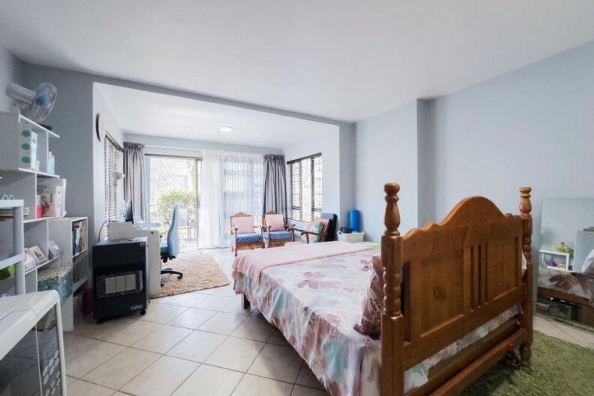 Spacious bedroom featuring tiled flooring, large windows, and a sliding glass door providing access to the outdoor area.