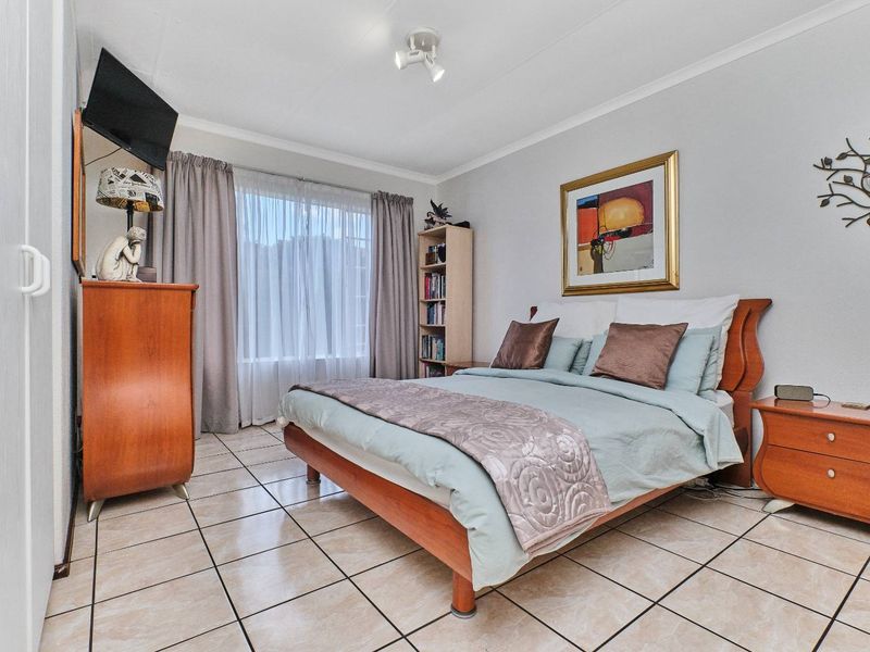 A well-lit bedroom featuring tiled flooring, a built-in wardrobe, and neutral wall finishes, providing a comfortable and functional living space.