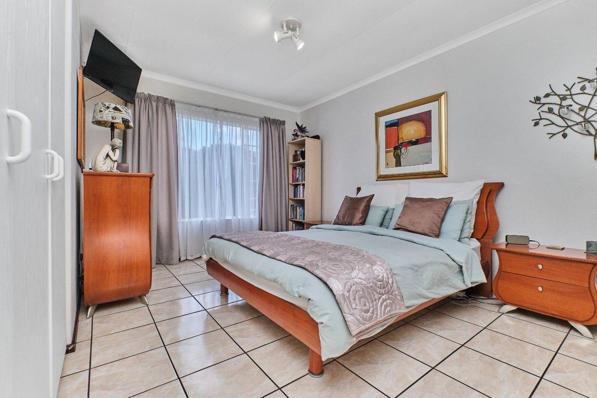 A well-lit bedroom featuring tiled flooring, a built-in wardrobe, and neutral wall finishes, providing a comfortable and functional living space.