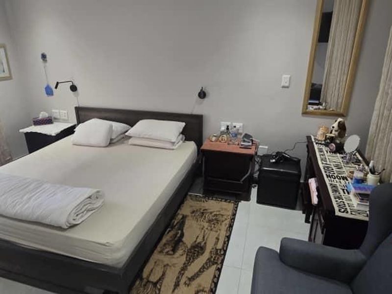 A functional bedroom featuring tiled flooring, wall-mounted reading lights, and large windows with curtains, providing a comfortable and well-lit sleeping space.