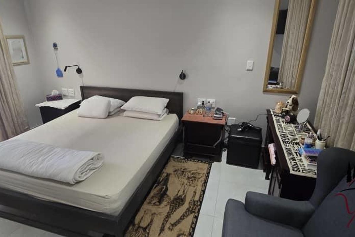 A functional bedroom featuring tiled flooring, wall-mounted reading lights, and large windows with curtains, providing a comfortable and well-lit sleeping space.