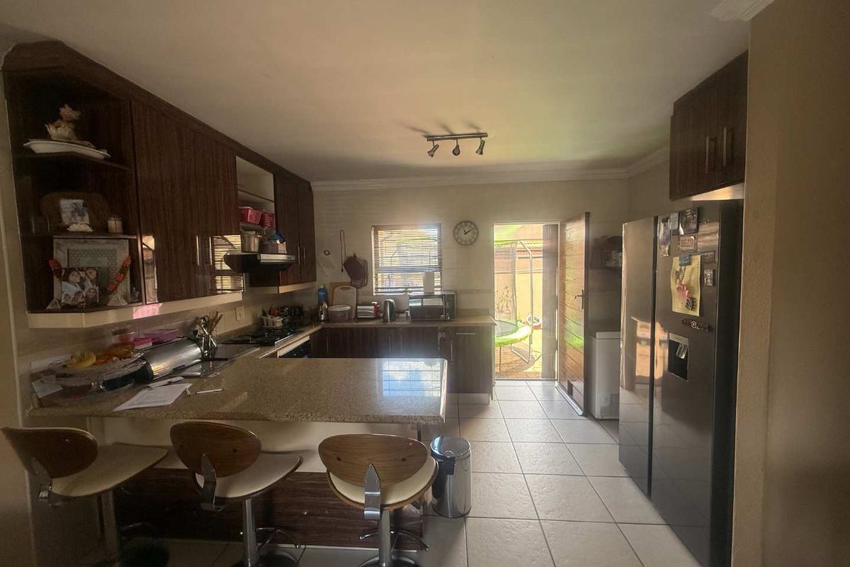 A functional kitchen featuring dark wood cabinetry, granite countertops, a breakfast nook, and tiled flooring with direct access to the rear exterior.