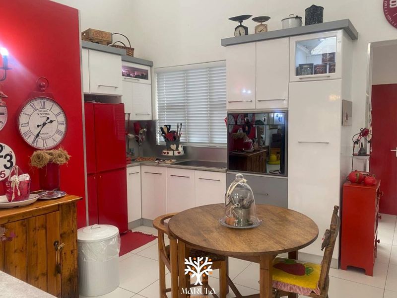 A compact kitchen featuring white cabinetry, stainless steel backsplash, and built-in oven, finished with tiled flooring and venetian blinds.