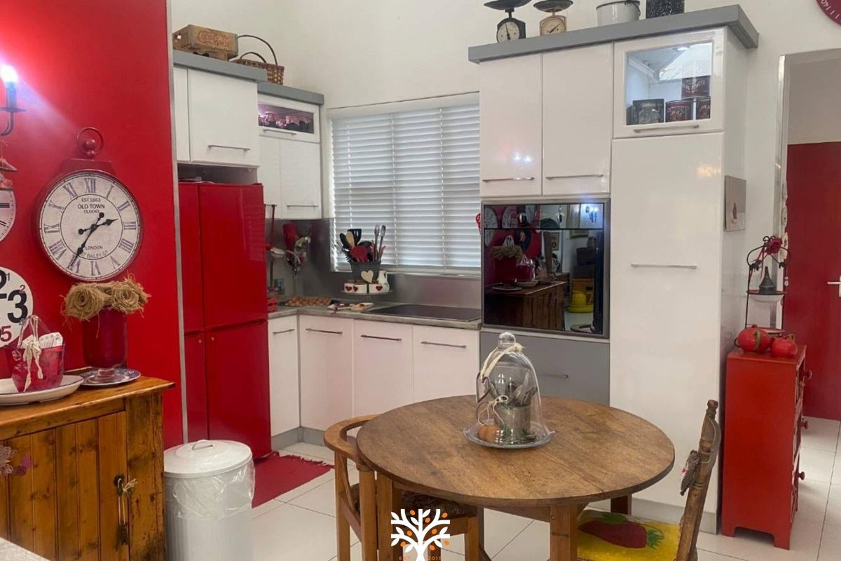 A compact kitchen featuring white cabinetry, stainless steel backsplash, and built-in oven, finished with tiled flooring and venetian blinds.