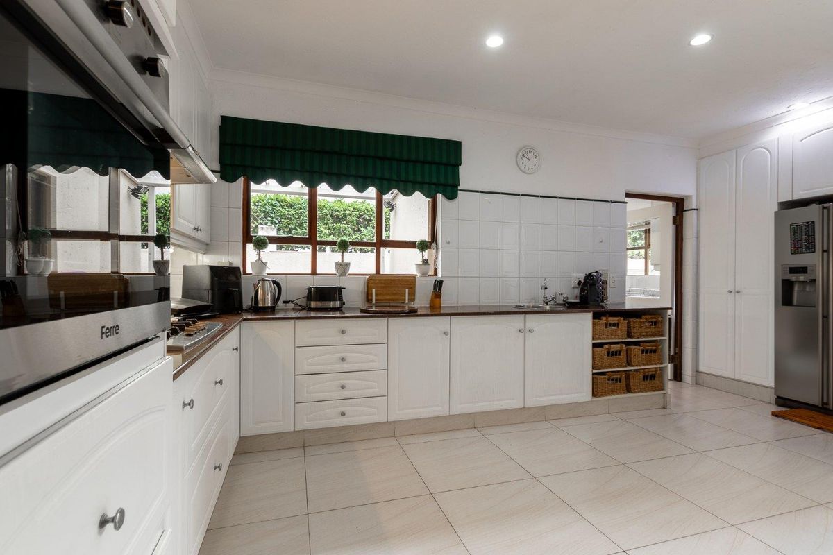 A functional kitchen featuring white cabinetry, tiled splashbacks, a built-in oven, and a gas hob, with tiled flooring throughout.