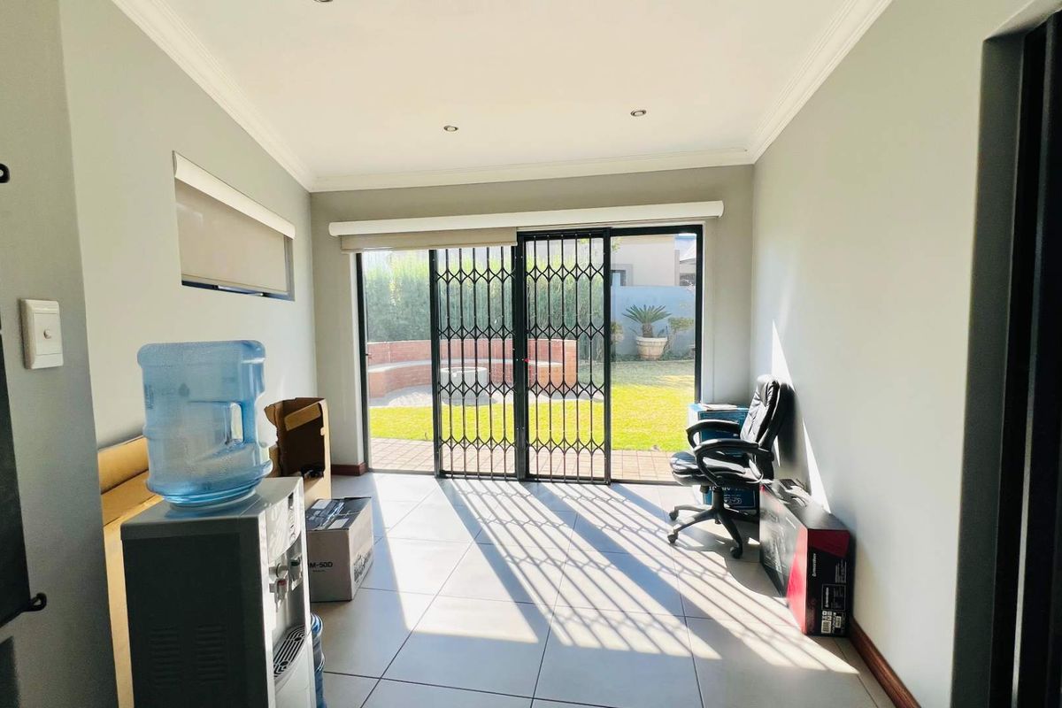 Bright living area featuring tiled floors, recessed lighting, and a sliding glass door with security gate providing direct access to the rear garden.