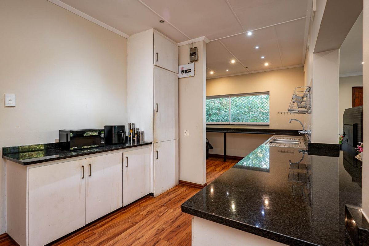 Functional kitchen featuring granite countertops, ample built-in cabinetry, stainless steel sink, and wood-look laminate flooring with recessed lighting.