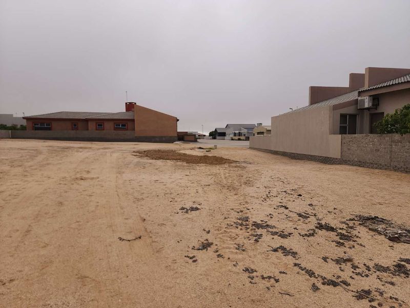 A view of a vacant residential plot showing surrounding boundary walls and neighboring properties.