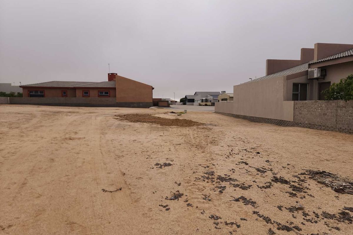 A view of a vacant residential plot showing surrounding boundary walls and neighboring properties.