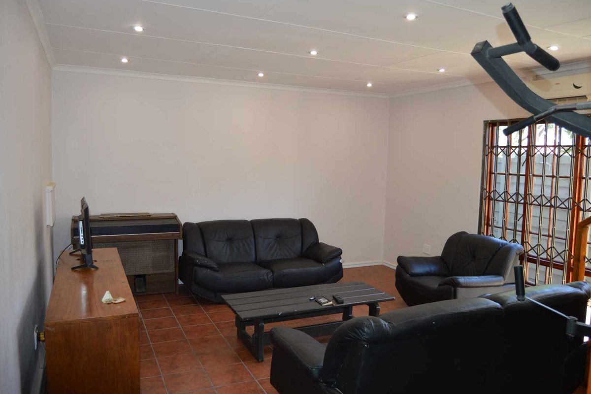 A living room featuring tiled flooring, recessed ceiling lighting, and a security gate on the window.