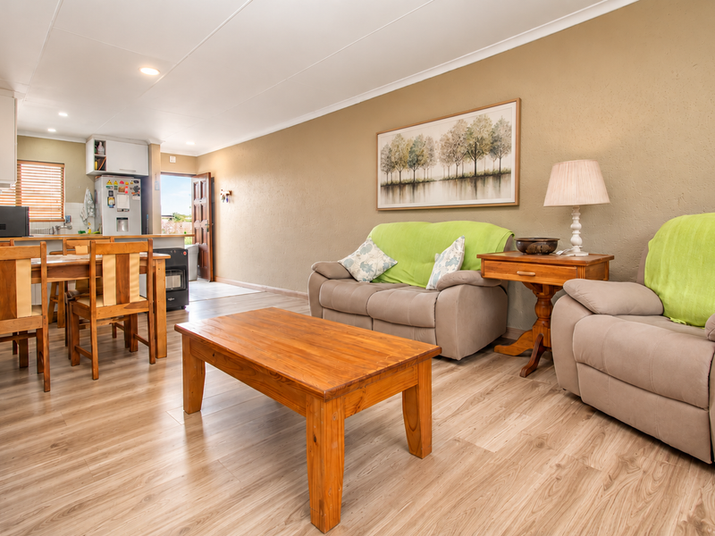 Open-plan living and dining area featuring laminate flooring, neutral walls, and an integrated kitchen space with functional cabinetry.