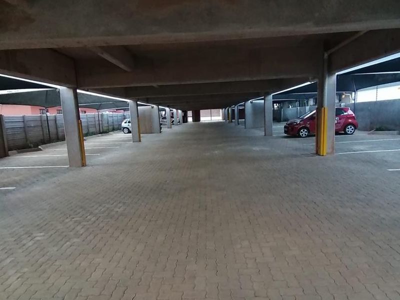 A covered parking garage area featuring concrete structural columns and paved parking bays.