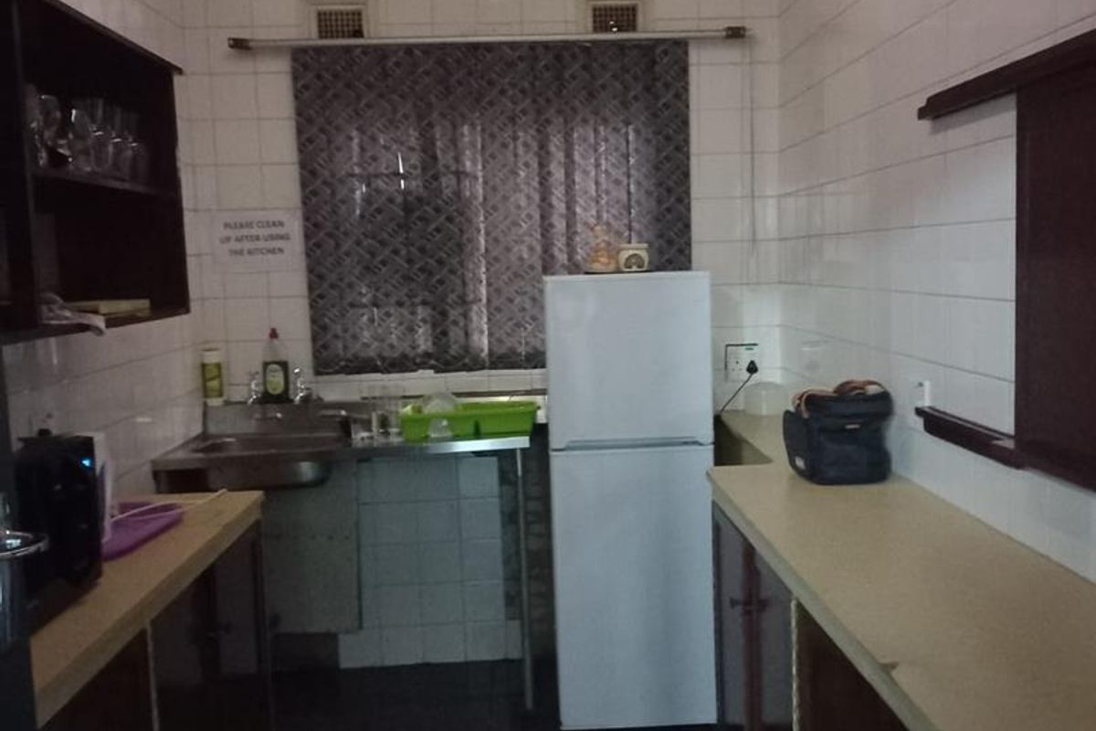 A functional industrial kitchen space featuring tiled walls, laminate countertops, and basic cabinetry, suitable for staff utility or food preparation.