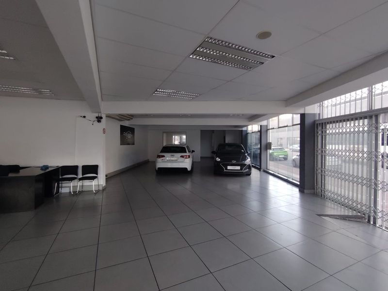 Spacious open-plan retail showroom featuring large glass windows, tiled flooring, and a suspended ceiling with integrated lighting, suitable for vehicle display.