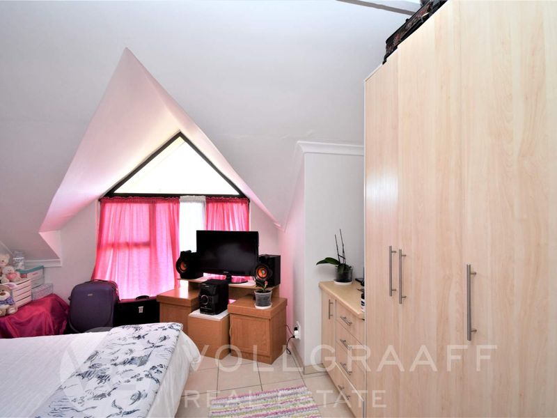 A bedroom featuring a pitched ceiling, a unique triangular window, and built-in wardrobe cabinetry.