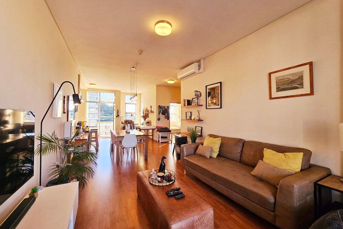 Spacious open-plan living and dining area featuring laminate flooring, split-system air conditioning, and large sliding glass doors leading to a balcony.