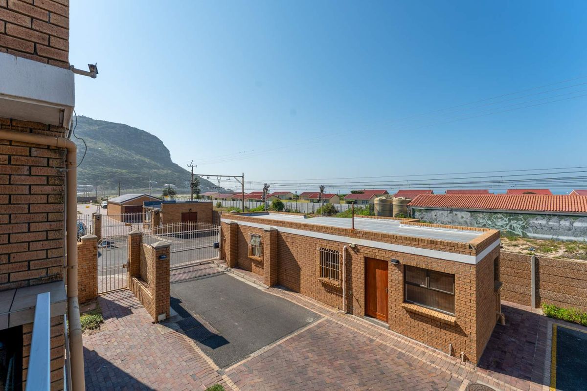 An elevated view of the rear exterior area featuring a brick building, paved driveway, and secure gated access.
