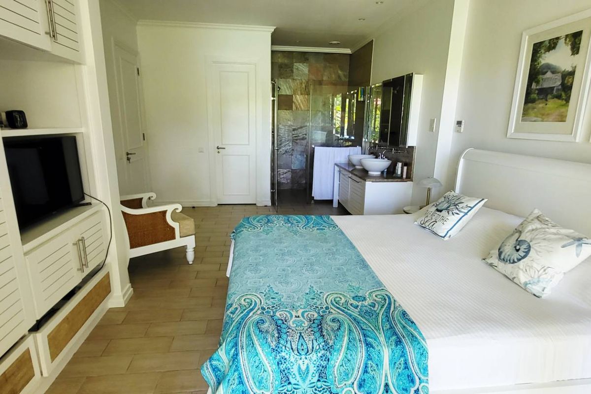 Spacious bedroom featuring built-in cabinetry, tiled flooring, and an en-suite bathroom with a double vanity and stone-tiled shower area.