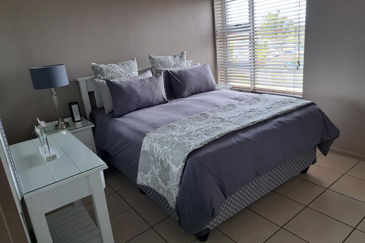 A bedroom featuring tiled flooring and horizontal window blinds, providing a functional and neutral living space.