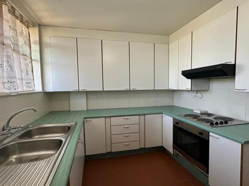 A functional kitchen featuring laminate countertops, built-in cabinetry, a double bowl sink, and integrated oven with electric hob.