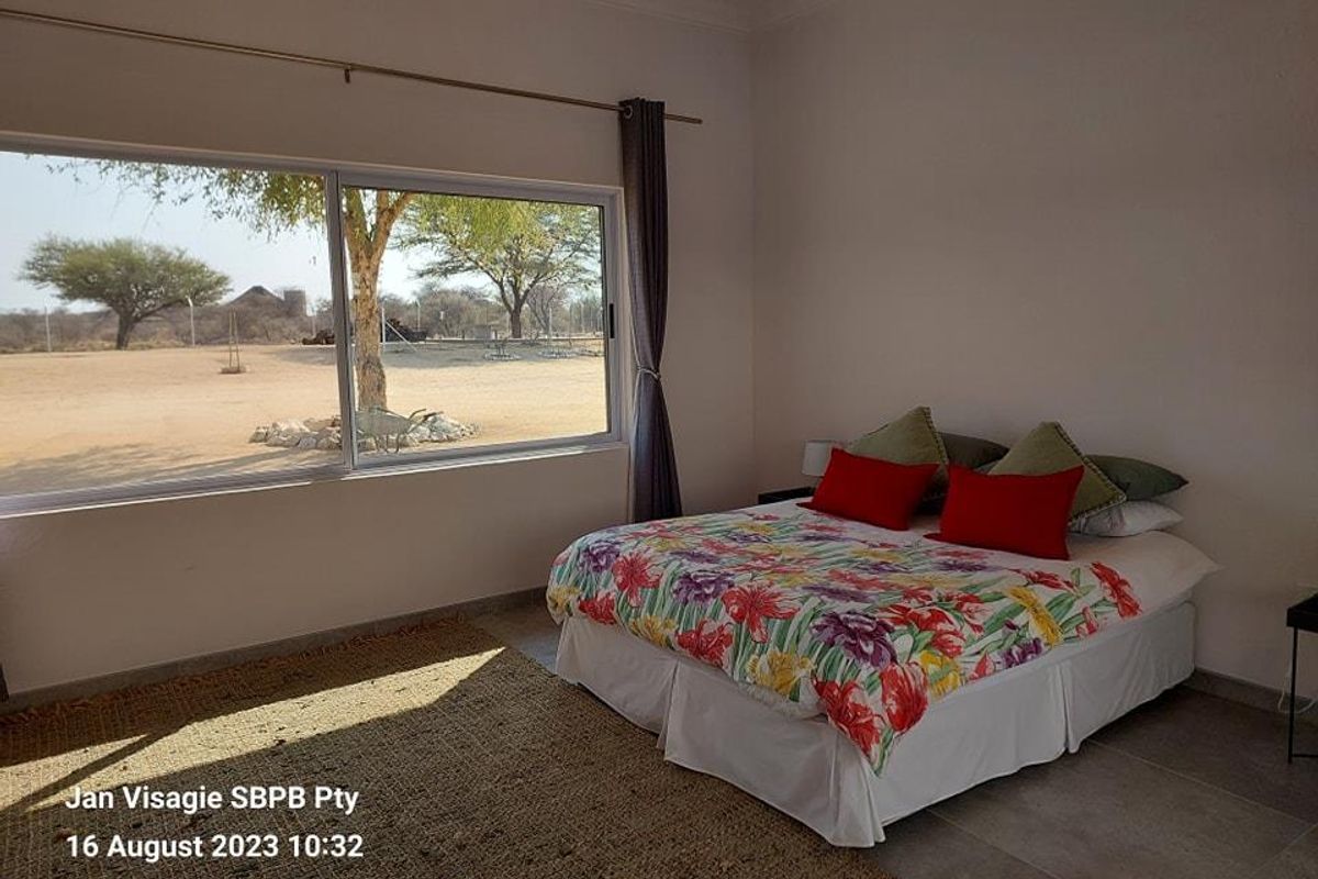 A bright bedroom featuring large sliding windows that offer expansive views of the surrounding landscape and natural light.