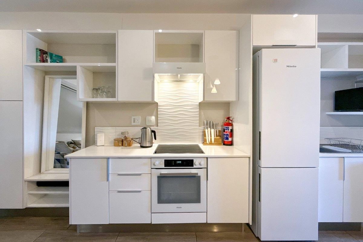 Modern kitchen featuring white cabinetry, integrated Miele oven and hob, textured tile splashback, and tiled flooring.