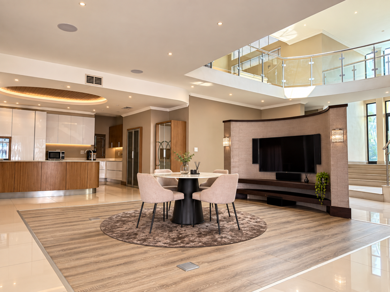 Spacious open-plan living and kitchen area featuring a curved media wall, modern cabinetry, and a mezzanine level with glass balustrades.