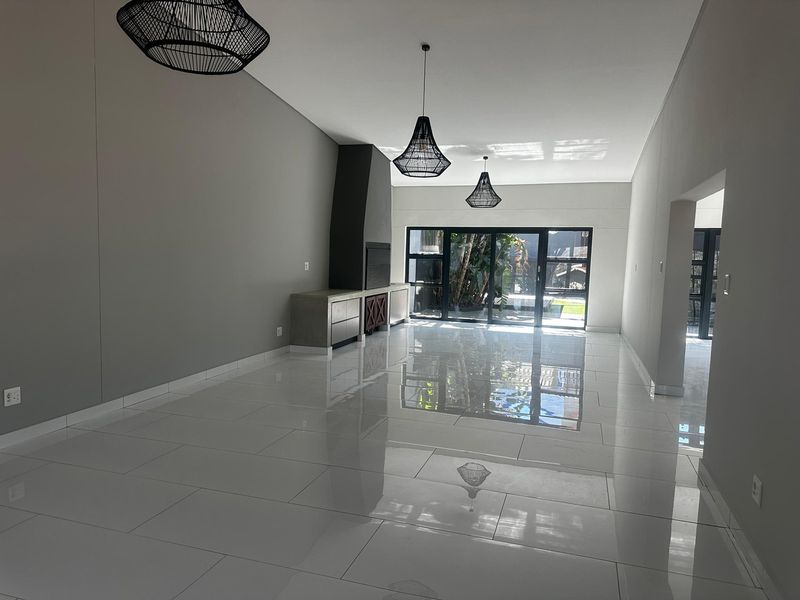 Spacious, modern living area featuring polished tile flooring, a built-in fireplace, and large sliding glass doors that open to the garden.