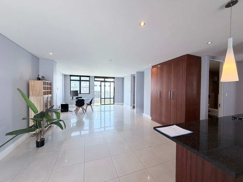 Spacious open-plan living area featuring polished tile flooring, recessed lighting, and modern built-in cabinetry with a granite-topped kitchen island.