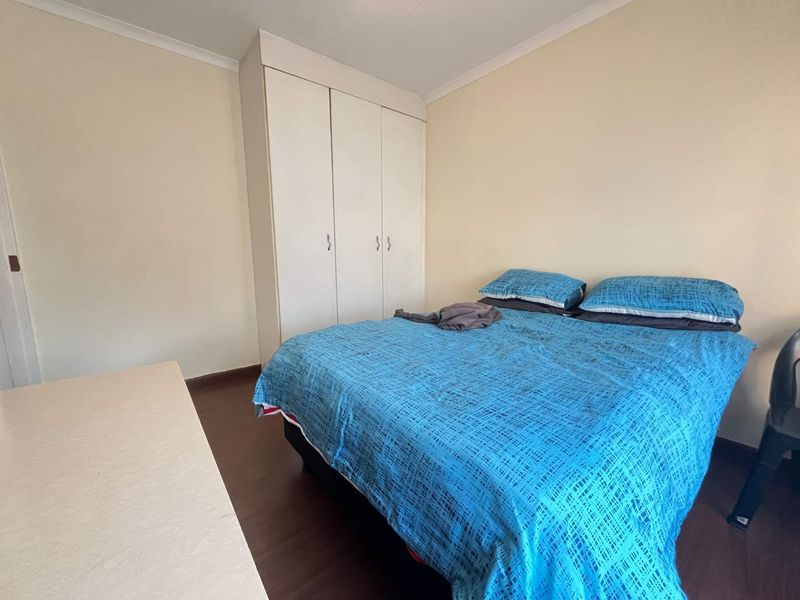 A functional bedroom featuring laminate flooring and a built-in wardrobe, offering a neutral base for potential interior updates.