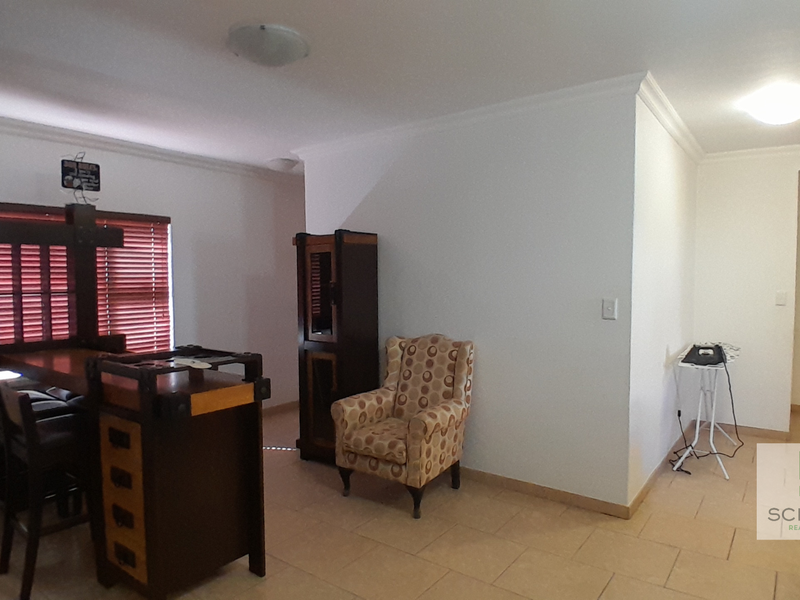 A living area featuring tiled flooring, cove cornicing, and venetian blinds, offering a neutral base for interior design updates.