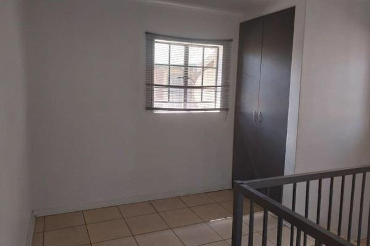 A simple, empty bedroom featuring tiled flooring and a built-in wardrobe, providing a clean and functional space.