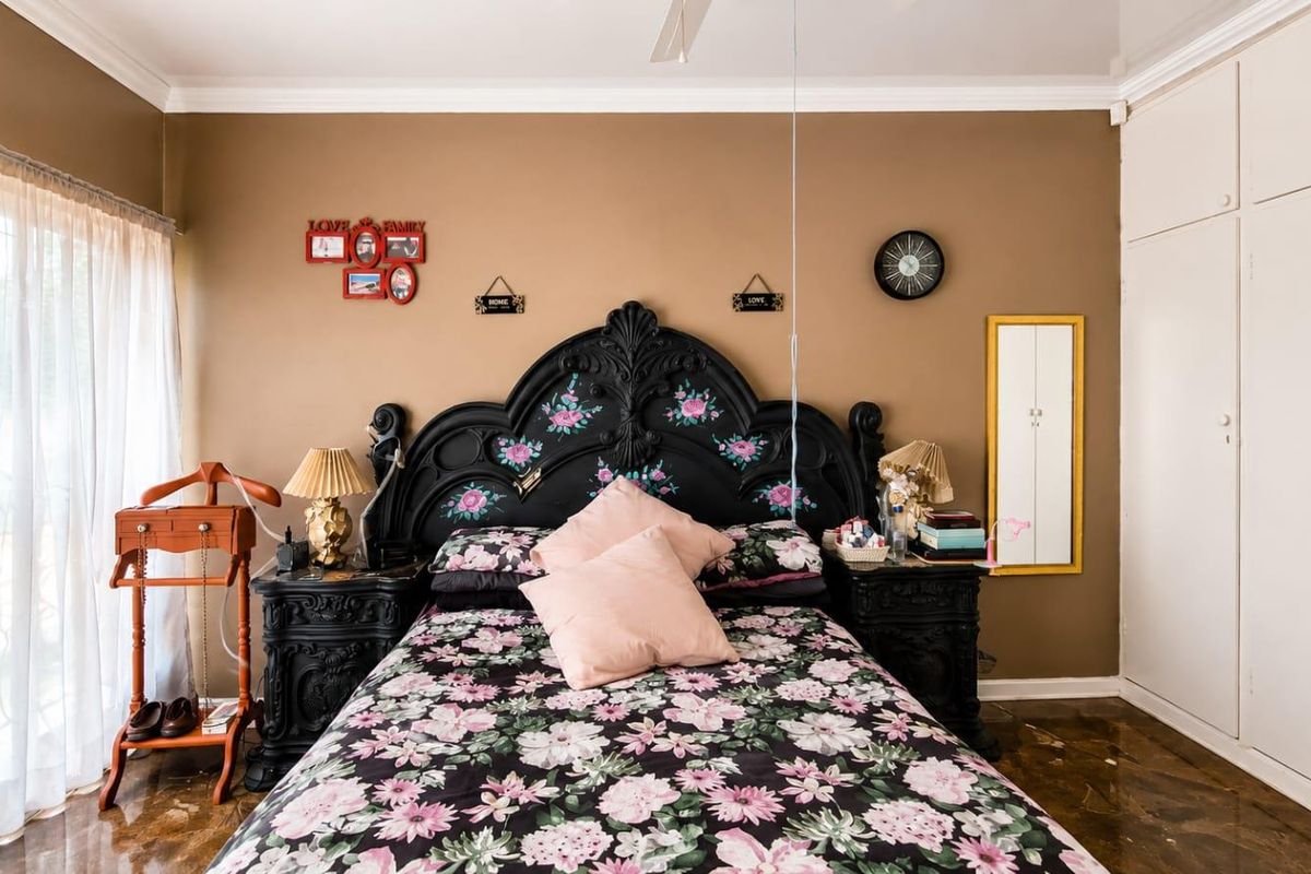 A bedroom featuring built-in cupboards, tiled flooring, and a ceiling fan, offering a functional space with direct access to natural light.