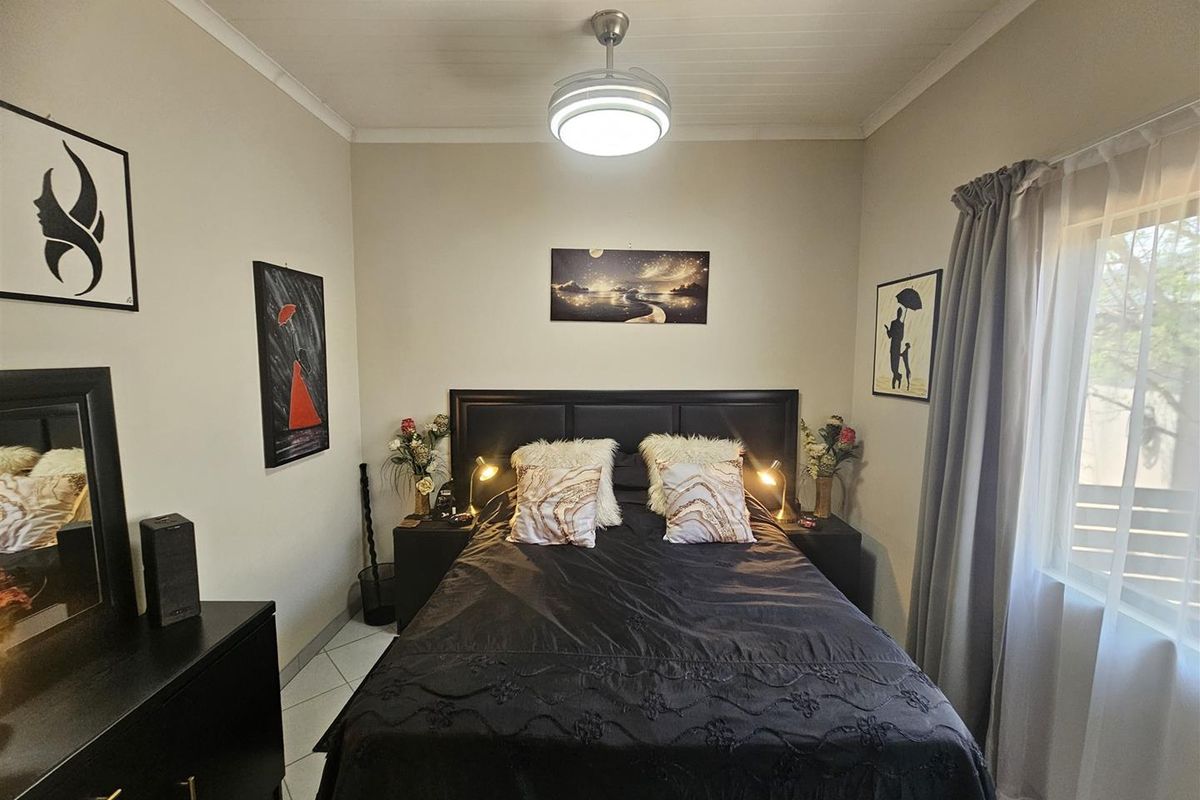 A well-maintained bedroom featuring tiled flooring, a central ceiling fan, and neutral wall finishes, providing a comfortable and functional sleeping space.