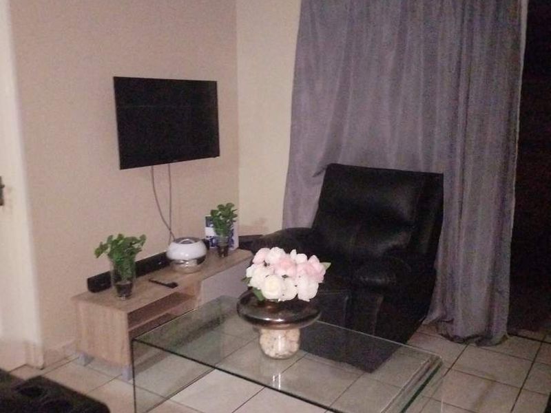 A compact living room area featuring tiled flooring and neutral wall finishes, providing a functional space for relaxation.