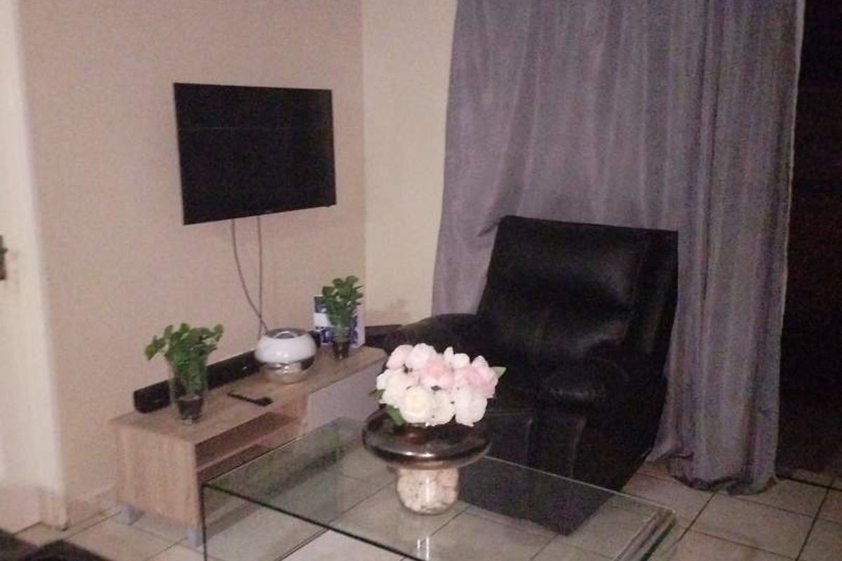 A compact living room area featuring tiled flooring and neutral wall finishes, providing a functional space for relaxation.