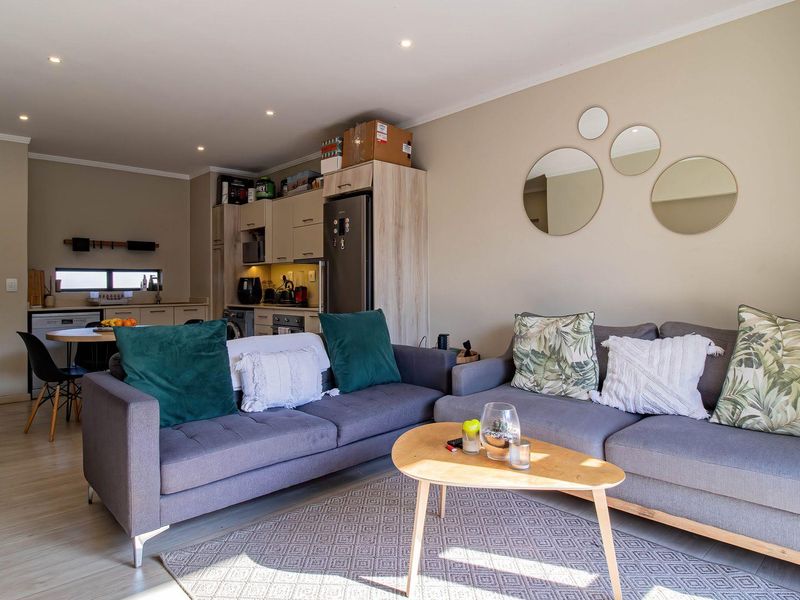 Open-plan living area featuring a modern kitchen with built-in cabinetry and integrated appliances, seamlessly flowing into a comfortable lounge space.