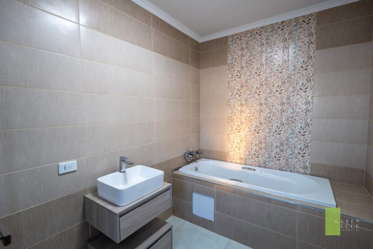 Modern bathroom featuring a built-in bathtub with decorative tiled accent wall and a contemporary wall-mounted vanity with vessel sink.
