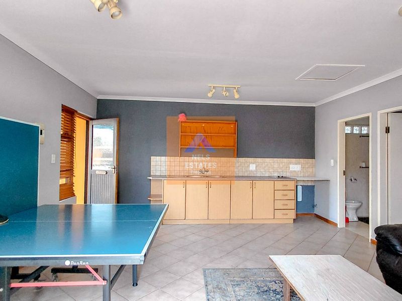Open plan living area featuring a kitchenette with built-in cabinetry, tiled flooring, and direct access to an adjacent bathroom.