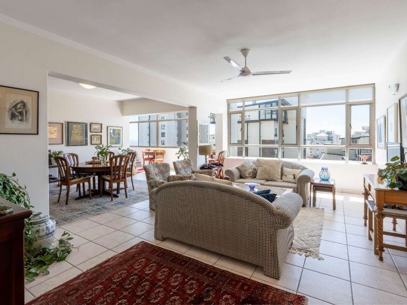 Spacious open-plan living and dining area featuring large windows, tiled flooring, and a ceiling fan, offering a bright and airy atmosphere.