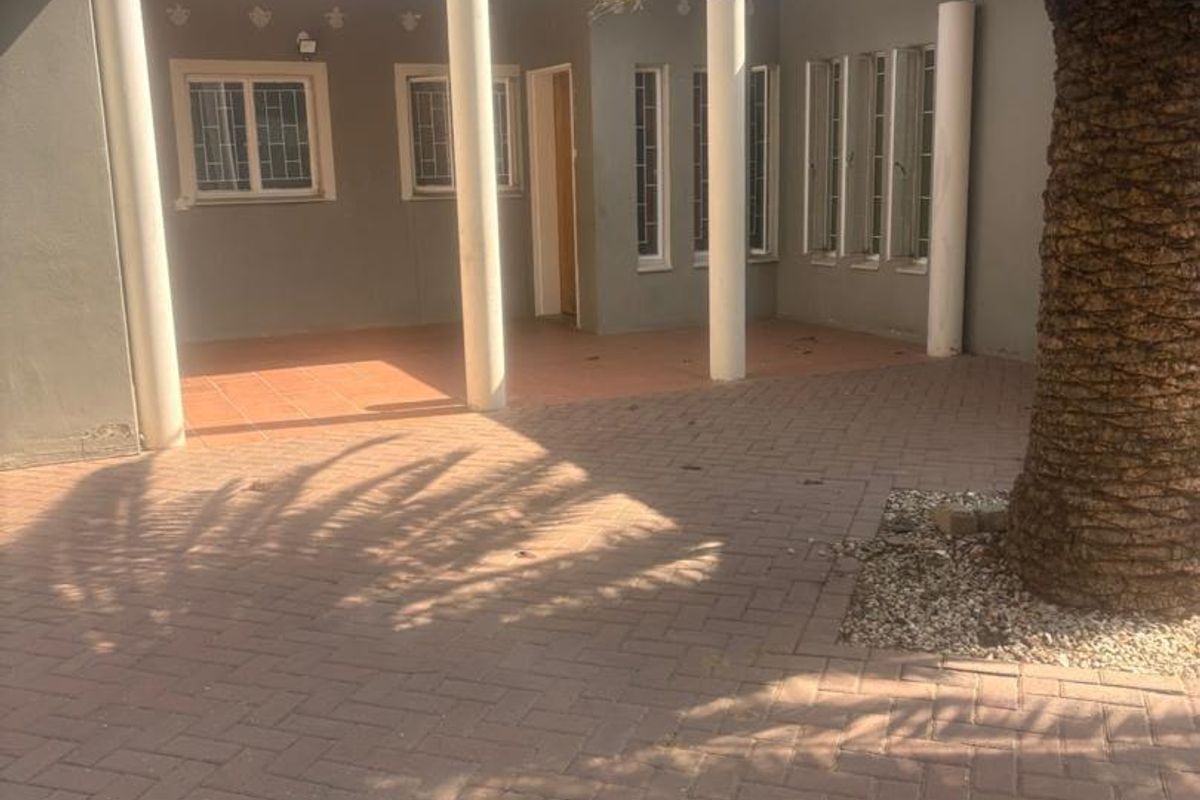 A covered patio area featuring structural columns, tiled flooring, and paved outdoor space, providing a functional area for outdoor living.
