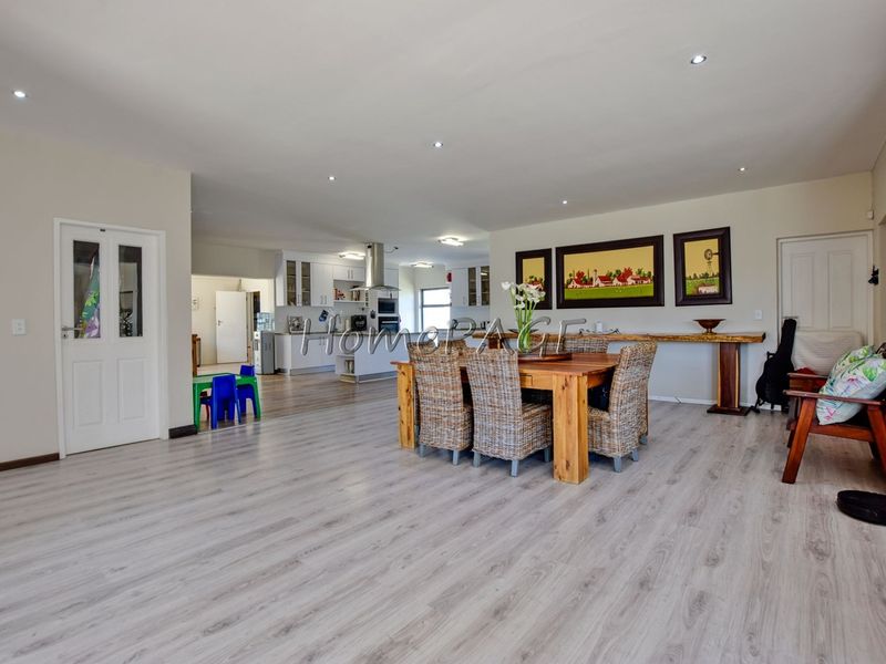 Spacious open-plan living and dining area featuring modern laminate flooring, recessed lighting, and a well-appointed kitchen with built-in cabinetry and appliances.